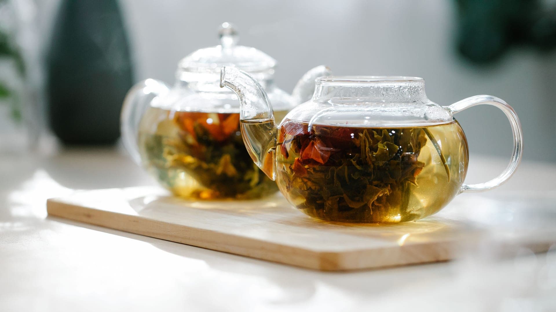 Glass teapot with loose leaf tea brewing on a wooden table